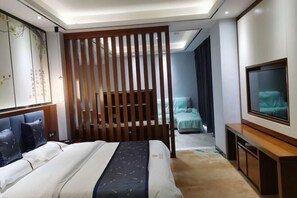 A hotel room with a bed, a TV, a desk, and a sliding door. - Jingan Haoting Hotel (Gengma)