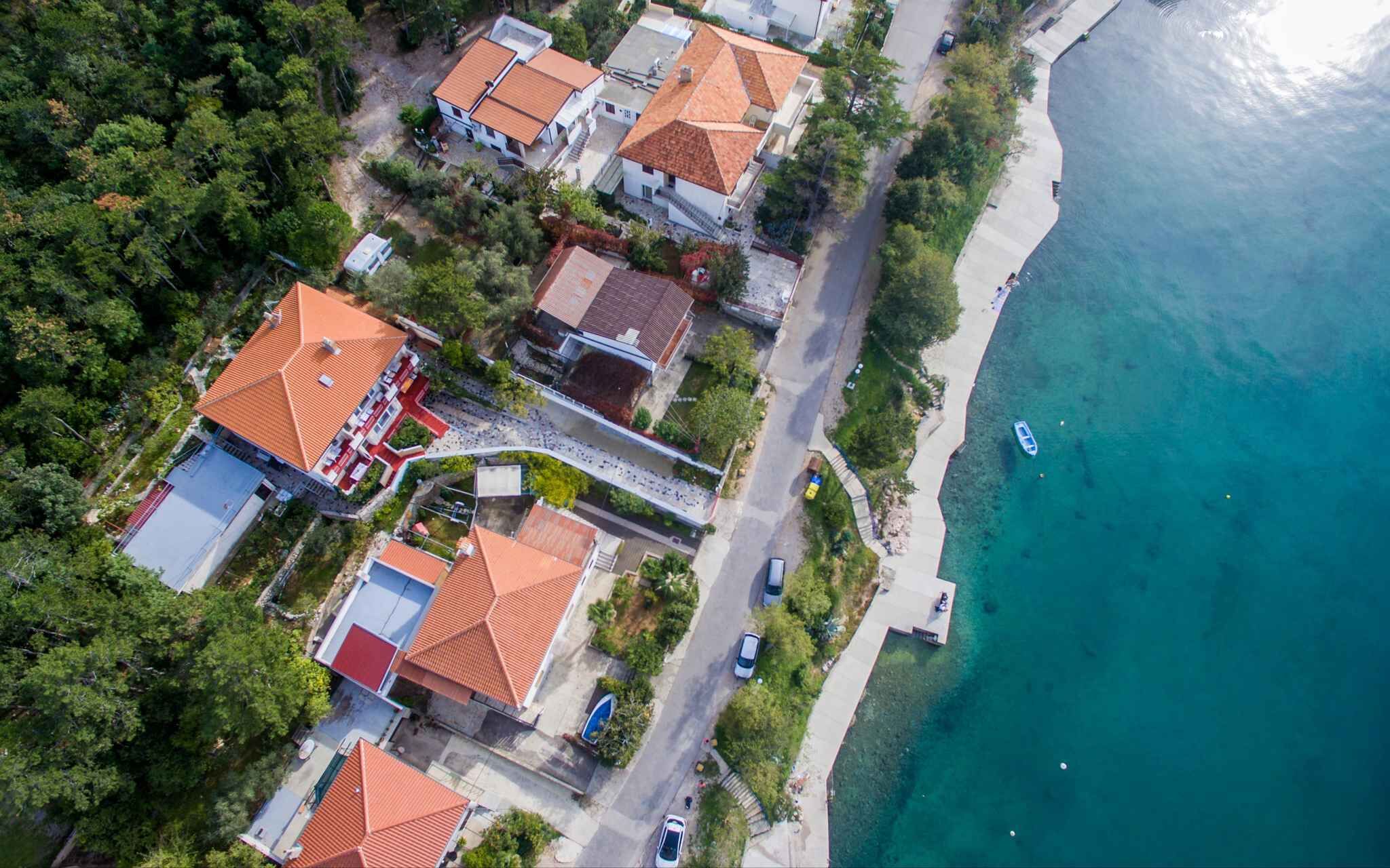 An aerial view of a coastal residential area with houses, a beach, and a boat.