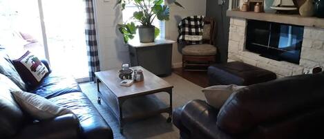 En stue med pejs, sofa, sofabord og en potteplante.