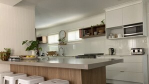 Una cocina moderna con una isla central, taburetes de bar, microondas y tostadora.