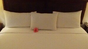 A neatly made bed with white linens and a single red flower. - Condos Portico (Mazatlán)