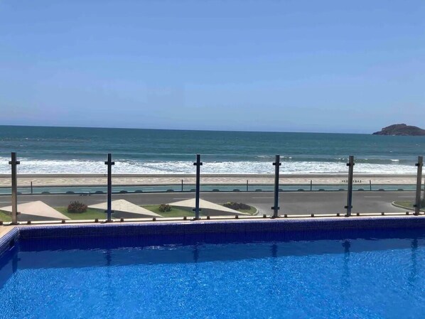 A swimming pool with a view of the beach and ocean.