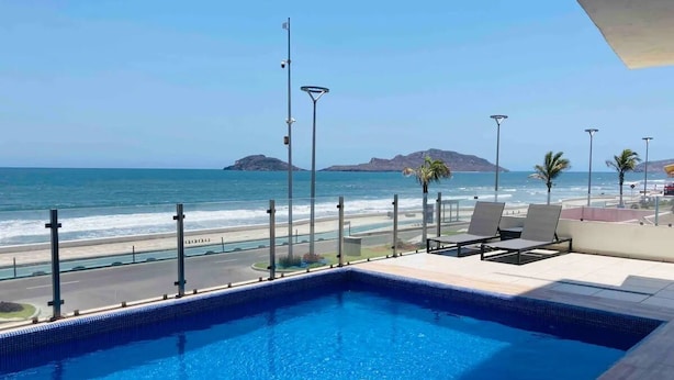 A swimming pool with a view of the ocean and beach. - Condos Portico (Mazatlán)