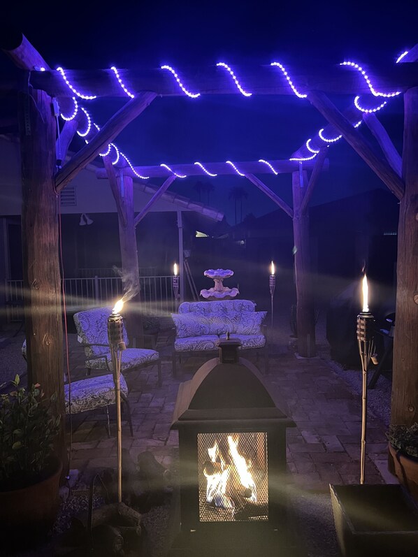 An outdoor patio area with a pergola, string lights, a fire feature, and seating. - Big Game House Rental in Glendale! 5bed/3bath - Pool, Putting Green & Much More! (Glendale)