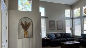 A spacious living room with a black leather sofa, a coffee table, and a decorative vase on the wall. - Mesa Serenity Oasis (Mesa)