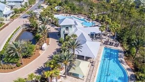 Eine Vogelperspektive auf einen Resortkomplex mit Schwimmbad, Palmen und einer Zufahrtsstraße.