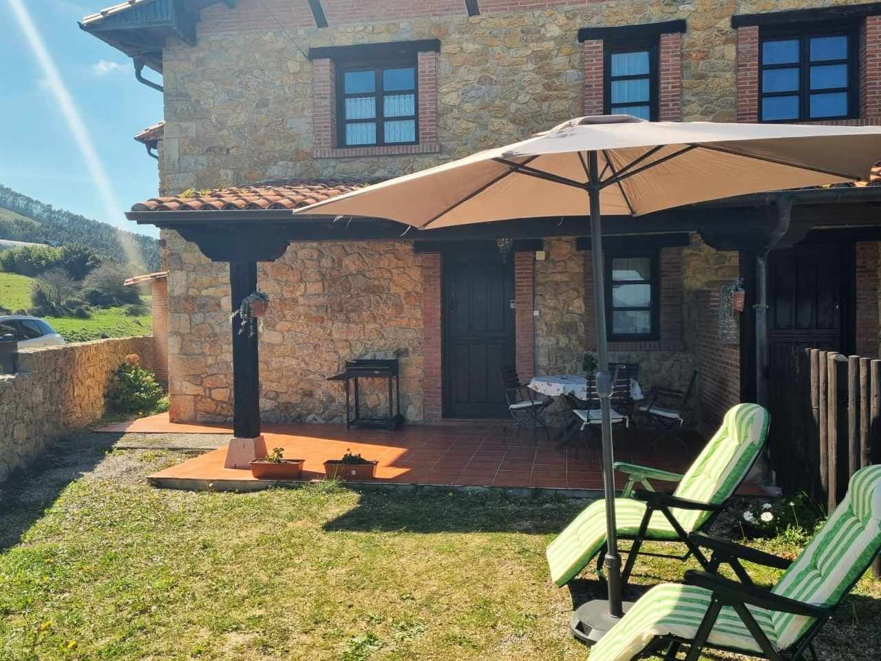 Un edificio de piedra con un patio amueblado y un gran paraguas.