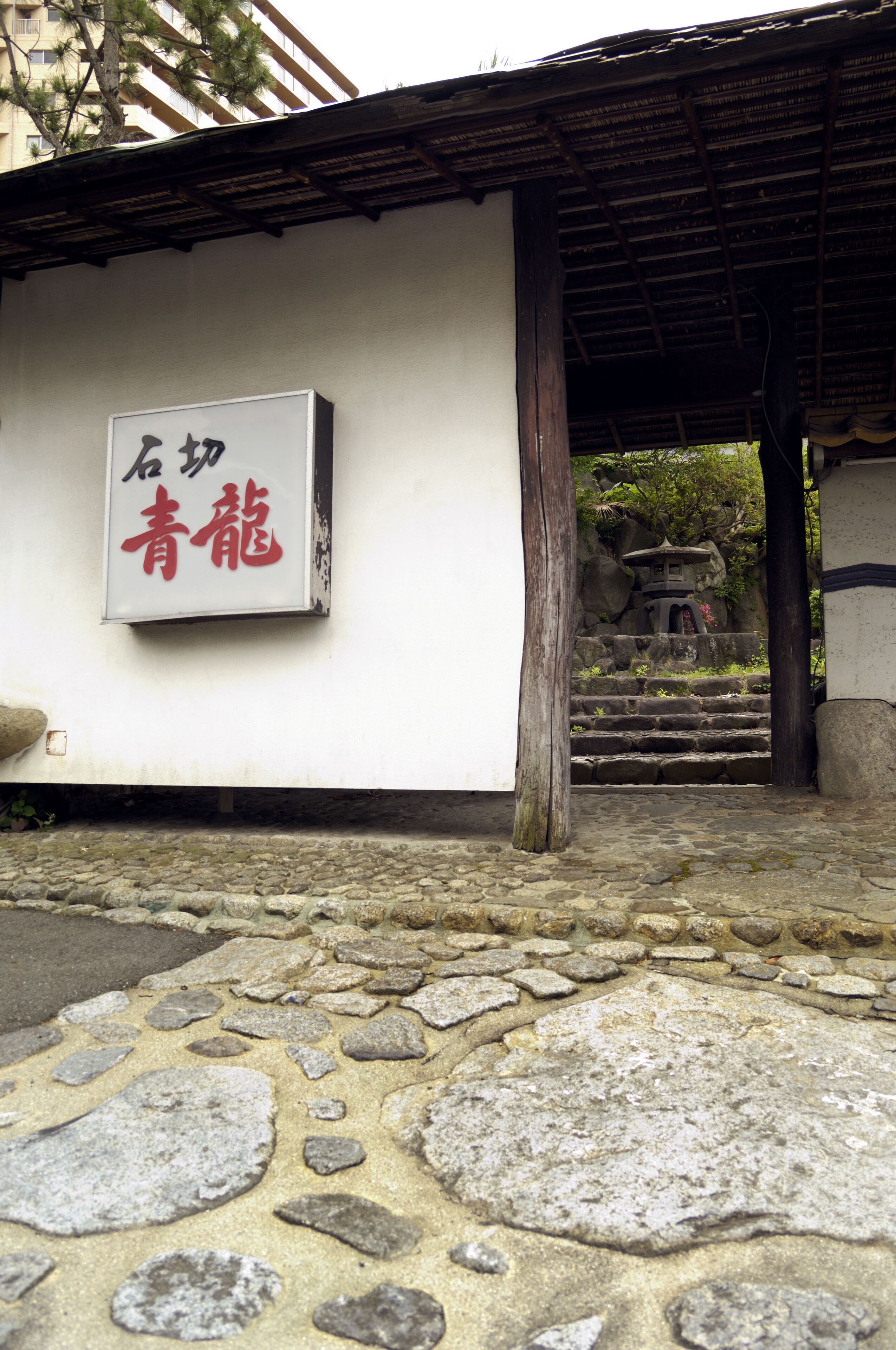 A stone-paved entrance with a traditional Japanese sign.