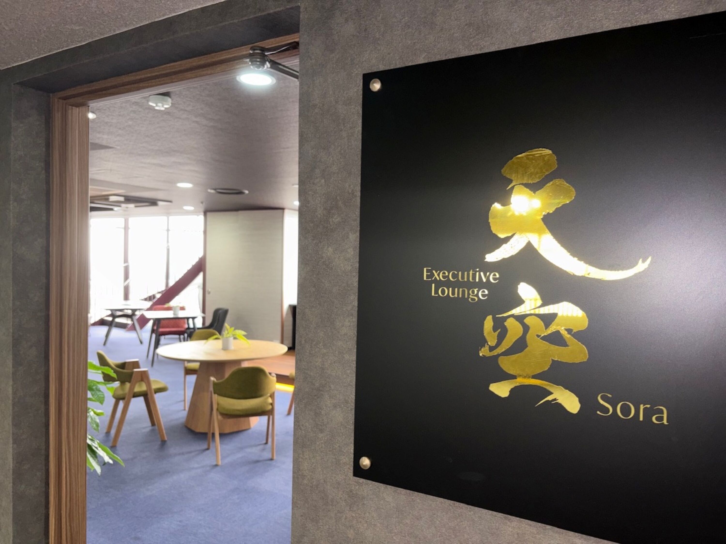 Een bordje voor de Executive Lounge, met een modern interieur zichtbaar op de achtergrond.