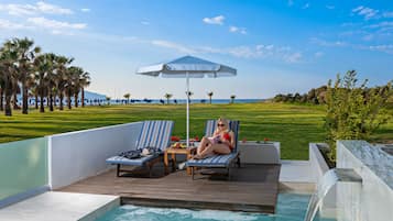 A poolside area with lounge chairs, a table, and a waterfall feature.