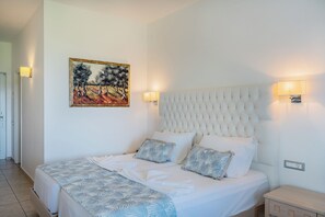 Una cama bien hecha con una colcha estampada, un cabecero con diseño acolchado y un cuadro en la pared.