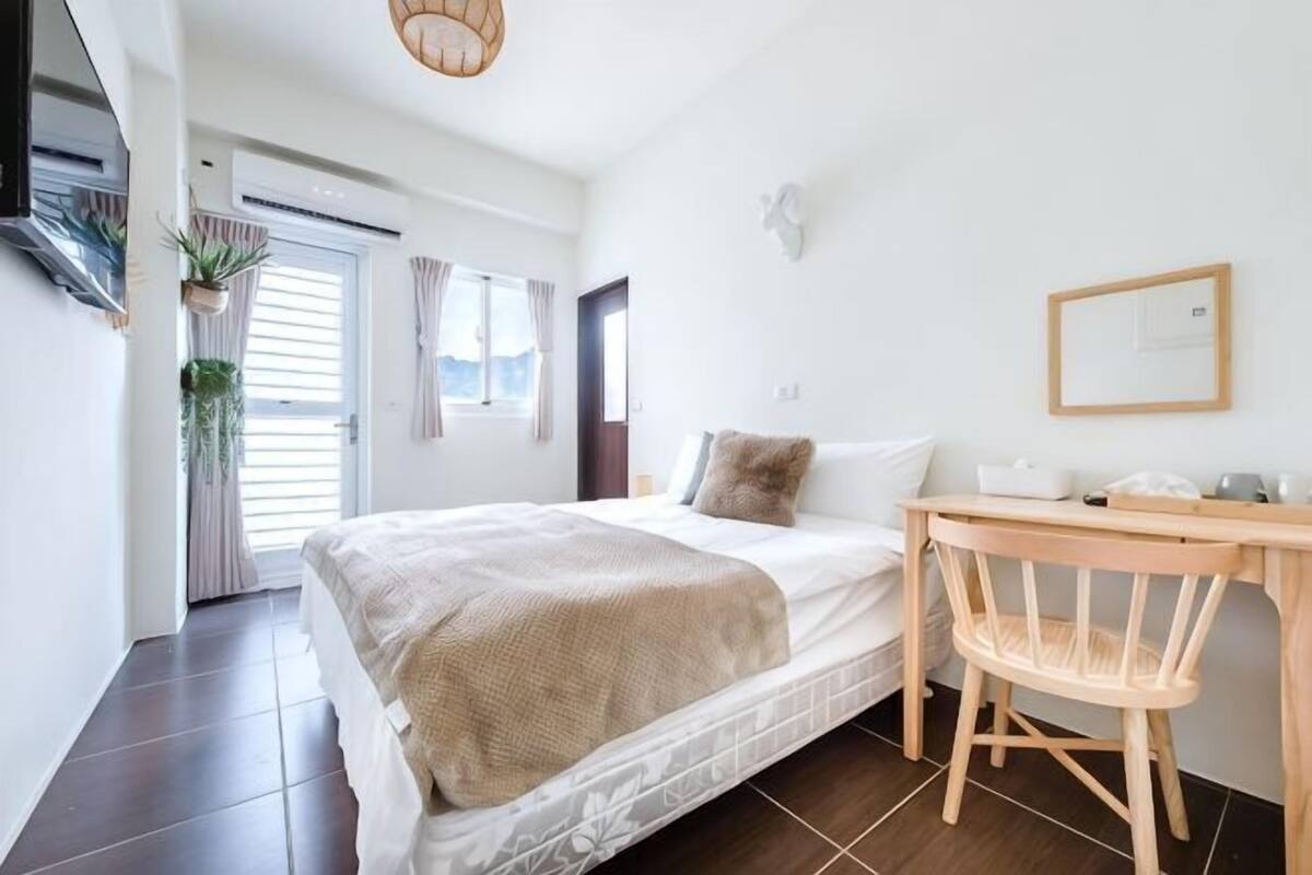 Une chambre à coucher avec un lit, un bureau, une chaise, une fenêtre et une porte.