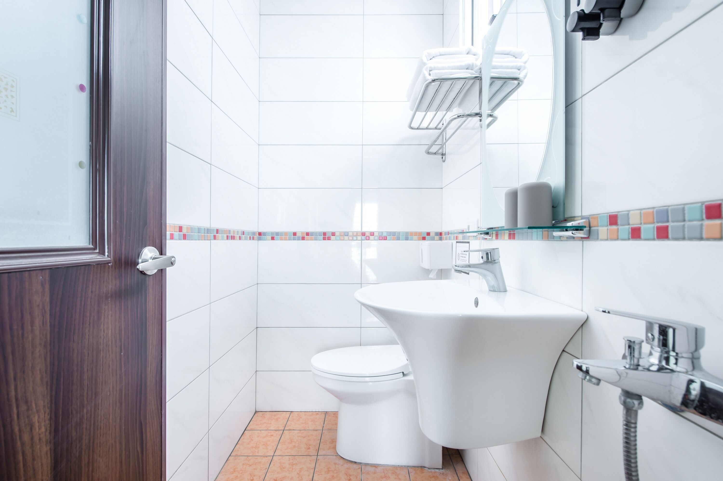 A modern bathroom with a white toilet, a white sink, and a shower area.