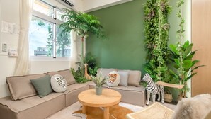A cozy living room with a beige sofa, a round wooden coffee table, and a variety of indoor plants. - Pet Friendly Bear Station Smart Stay (Taitung)