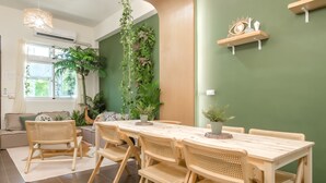 A dining area with a wooden table and chairs, surrounded by green walls and potted plants. - Pet Friendly Bear Station Smart Stay (Taitung)