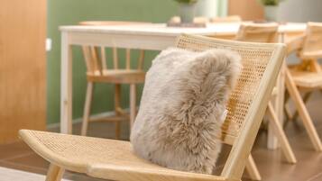 Una silla con un almohadón mullido en una habitación con pared verde y una mesa de madera.