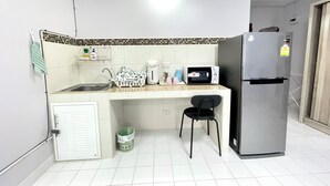 A compact kitchen with a sink, microwave, and refrigerator. - Impact Muangthong Condo C3 by Miles (Pak Kret)