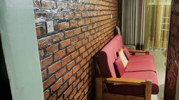 Une pièce avec un mur en briques, un banc en bois et un canapé rouge.