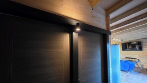 A modern interior with a dark sliding door, wooden ceiling beams, and a blue sofa in the background. - Tall Pines Lodge Dog Friendly, Nr Sutton on Sea (Sutton on sea)