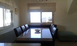 Un coin repas avec une table et des chaises, une fenêtre donnant sur un paysage agréable et un radiateur.