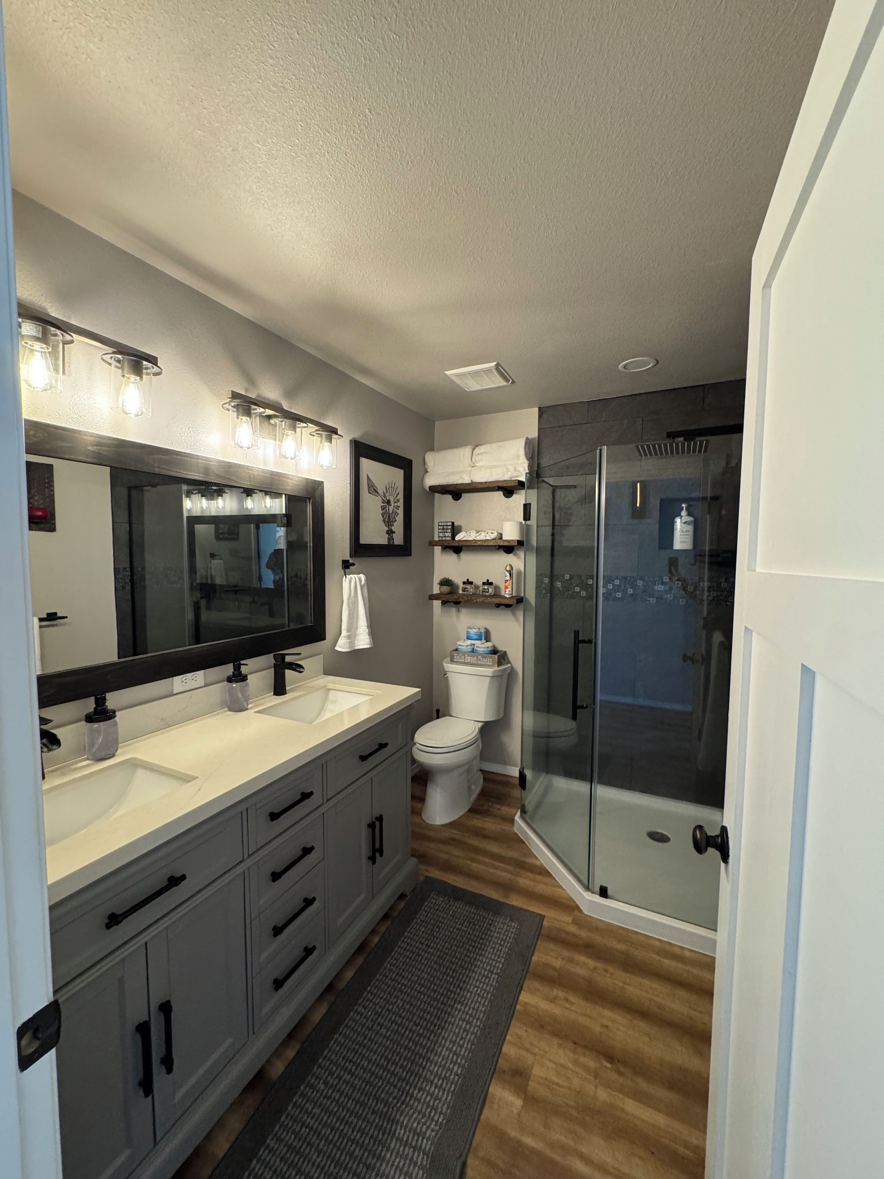 Une salle de bain moderne avec un meuble-lavabo double, un grand miroir, une douche à parois de verre et des toilettes.