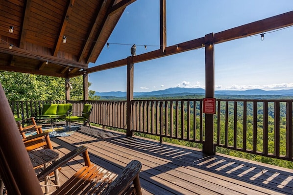 Une terrasse en bois avec des sièges d’extérieur, une rambarde et une vue sur les montagnes.