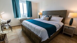 Ein ordentlich eingerichtetes Hotelzimmer mit Bett, Nachttischen, Schreibtisch und Stuhl.