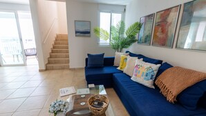 Ein modernes Wohnzimmer mit einem blauen Sofa, einem Glastisch und einer Treppe, die zu einem Außenbereich führt.