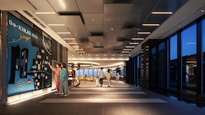 A modern hotel lobby with a large digital map display, a reception area, and a view of the cityscape through large windows.