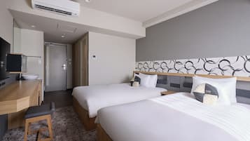 Habitación de hotel con dos camas, un escritorio, un televisor y un equipo de aire acondicionado.