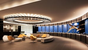 A modern lobby with a curved seating area, a central light fixture, and a large digital display wall.