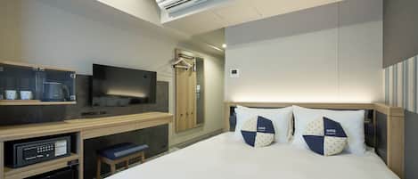 Une chambre d’hôtel équipée d’un lit, d’une télévision, d’un four à micro-ondes, d’un mini-réfrigérateur, d’un banc, d’un climatiseur et d’une armoire.