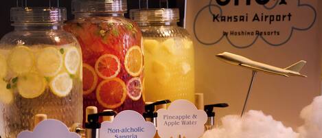 Three glass jars labeled with different beverages: Lemon Water, Non-alcoholic Sangria, and Pineapple & Apple Water.