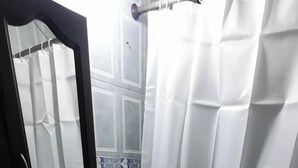 A bathroom with a blue toilet, a white shower curtain, and a mirror above the sink. - Comfortable apartment in Medellin (Medellin)