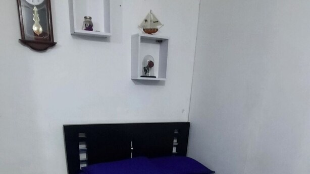 A bedroom with a bed, a wooden headboard, and a wall clock. - Comfortable apartment in Medellin (Medellin)