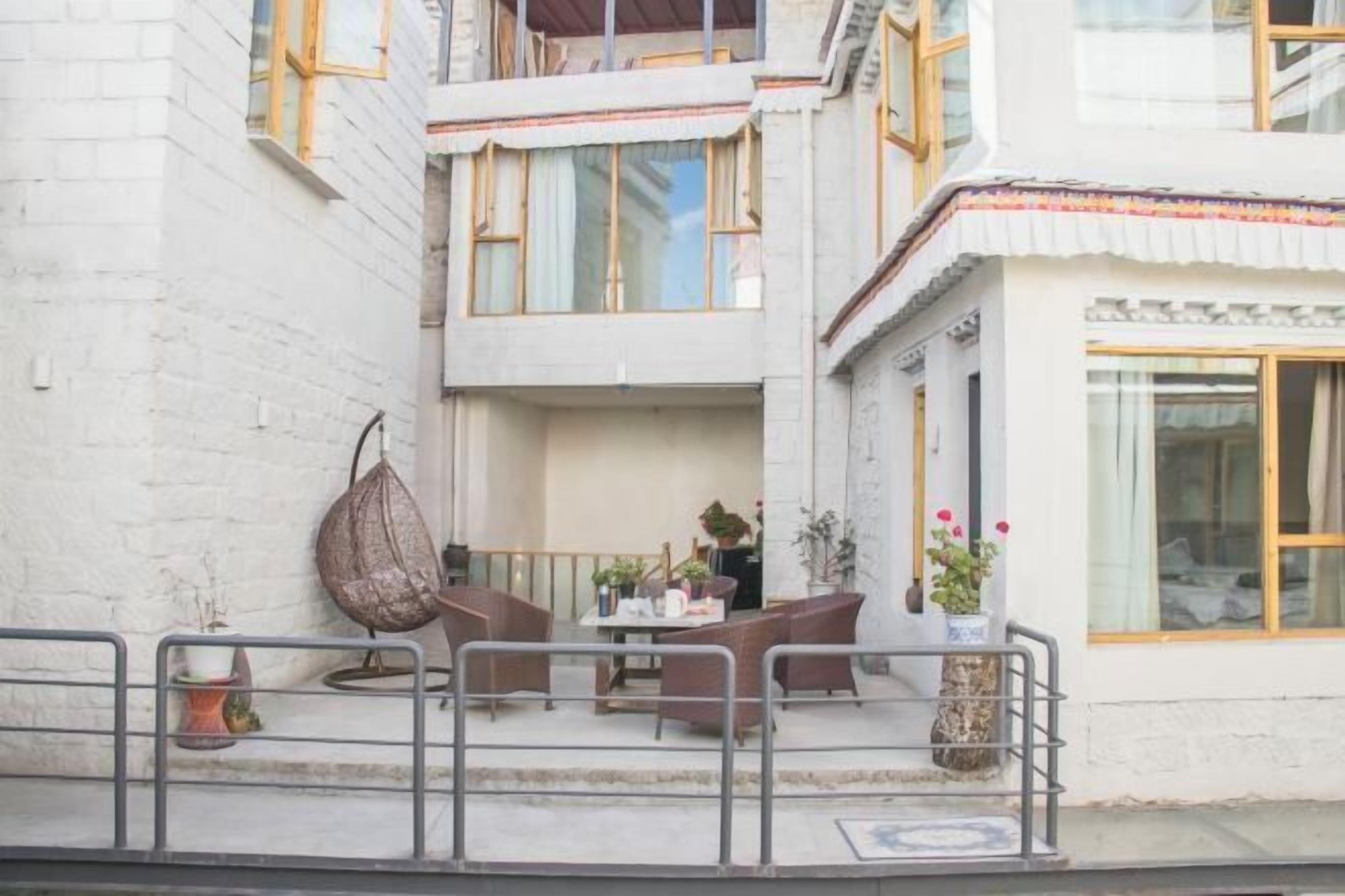 Ein Innenhof mit Außenbestuhlung, einer hängenden Pflanze und einem Blumentopf auf dem Balkon.