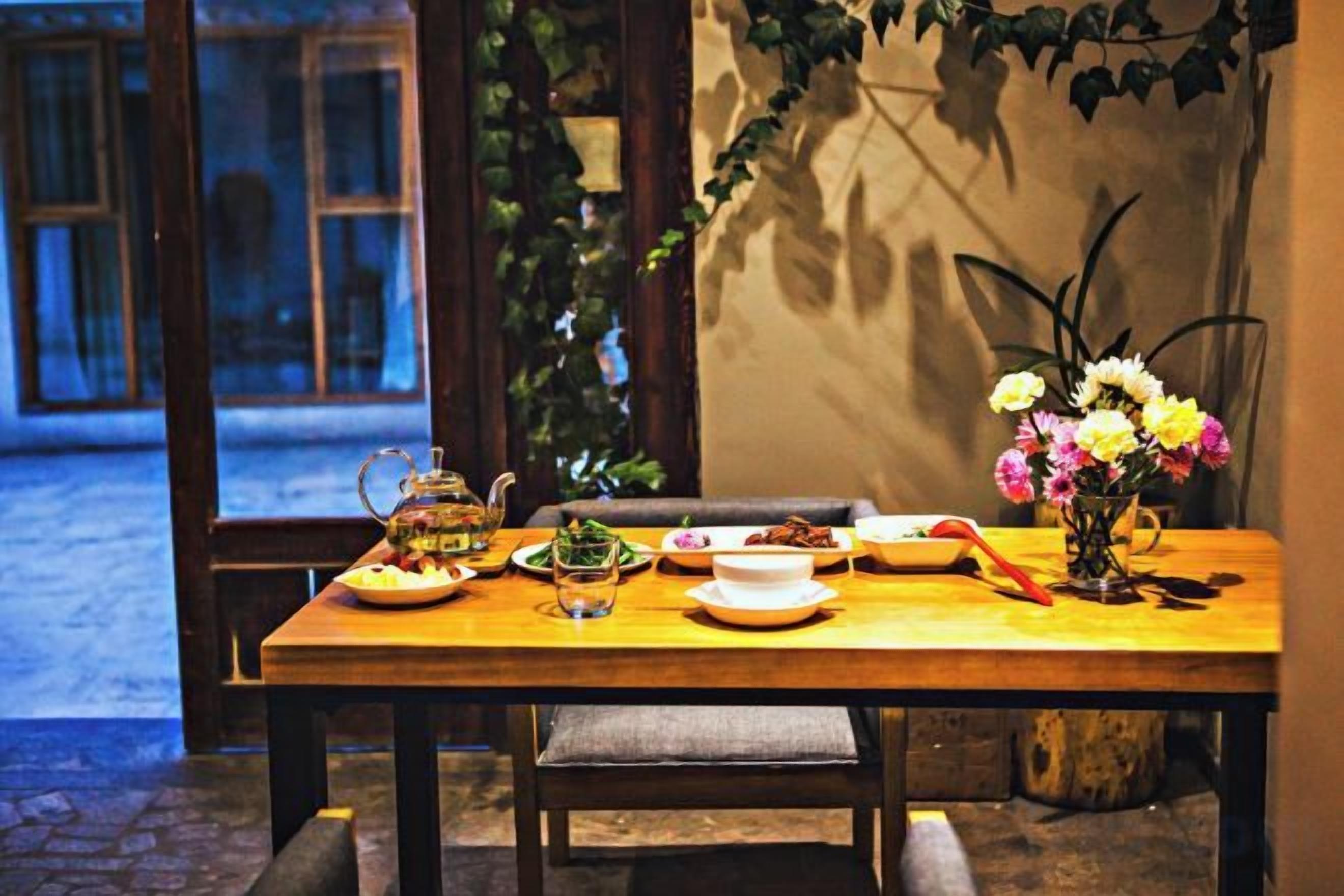 A dining table set with plates, a teapot, and a vase of flowers.