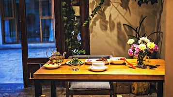 A dining table set with plates, a teapot, and a vase of flowers.