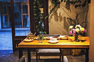 Una mesa de comedor dispuesta con platos, una tetera y un jarrón de flores.