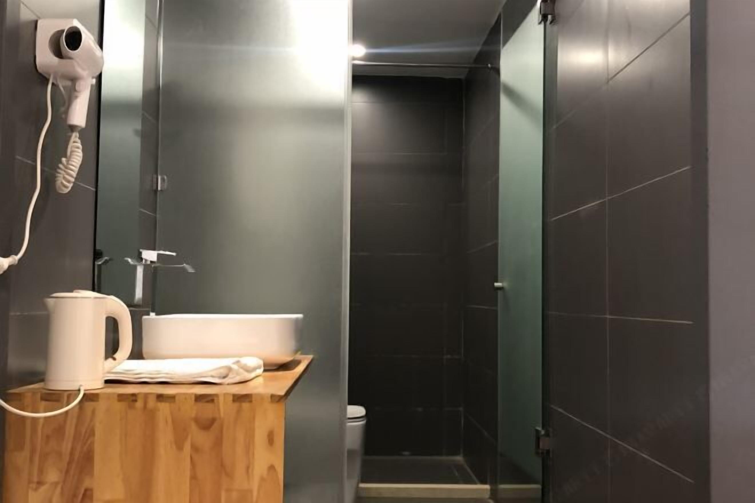 A bathroom with a wooden vanity, a hairdryer, and a toilet.