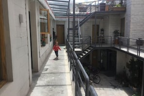 A narrow corridor with a staircase leading to an upper level, a bicycle, and potted plants.