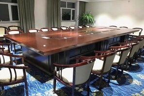 A conference room with a long table and chairs, a potted plant, and a window.