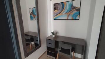 Una habitación con un espejo grande, un escritorio, una silla y un cuadro abstracto colgado en la pared.