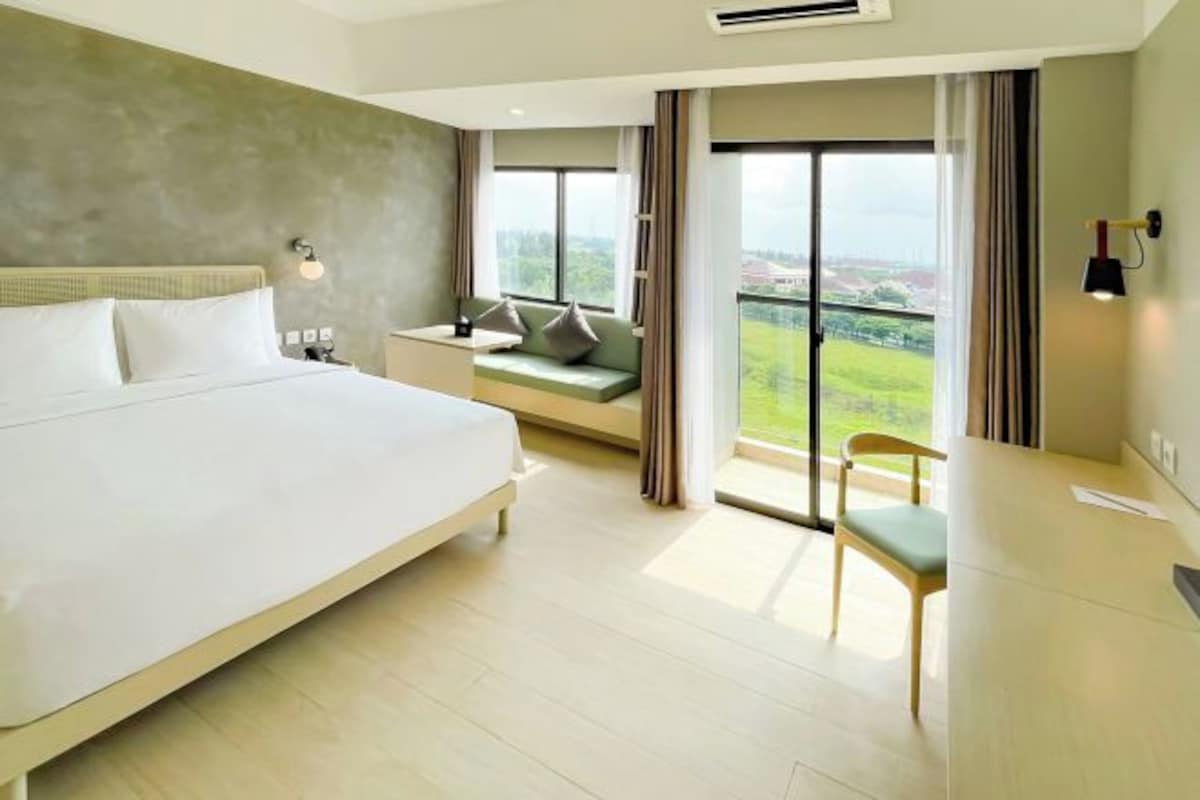 A hotel room with a large bed, a seating area with a view, and a balcony.