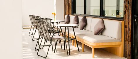 A modern outdoor seating area with a sofa and chairs, a small table, and a vase with flowers.