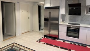 Et moderne køkken med et rustfrit stålkøleskab, indbygget ovn og mikroovn.