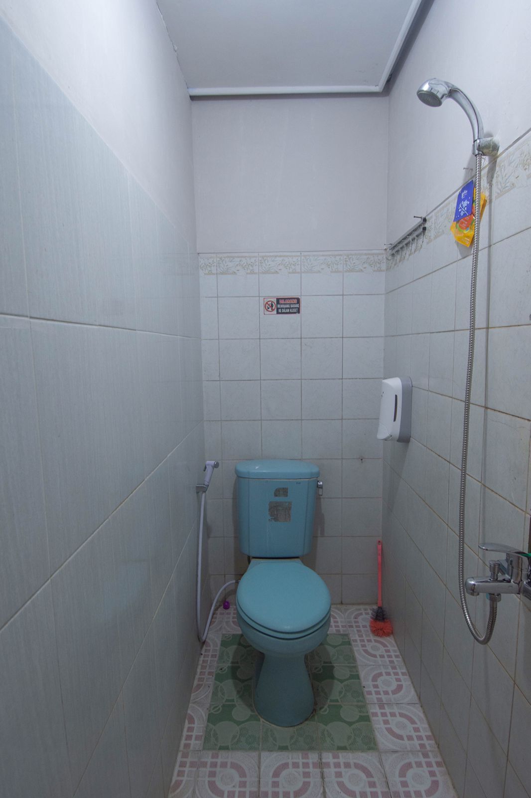 A small, compact bathroom with a toilet, a shower, and a hand dryer.