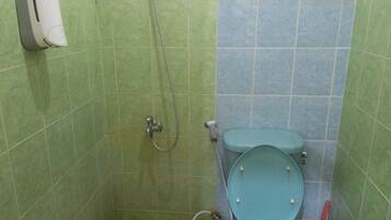 Un baño pequeño con inodoro, ducha y dispensador de jabón.
