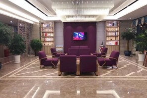 A lobby with a seating area, a television, and bookshelves. - Lavande Hotels (Huai'an Zhou Enlai Former Residence) (Huai'an)