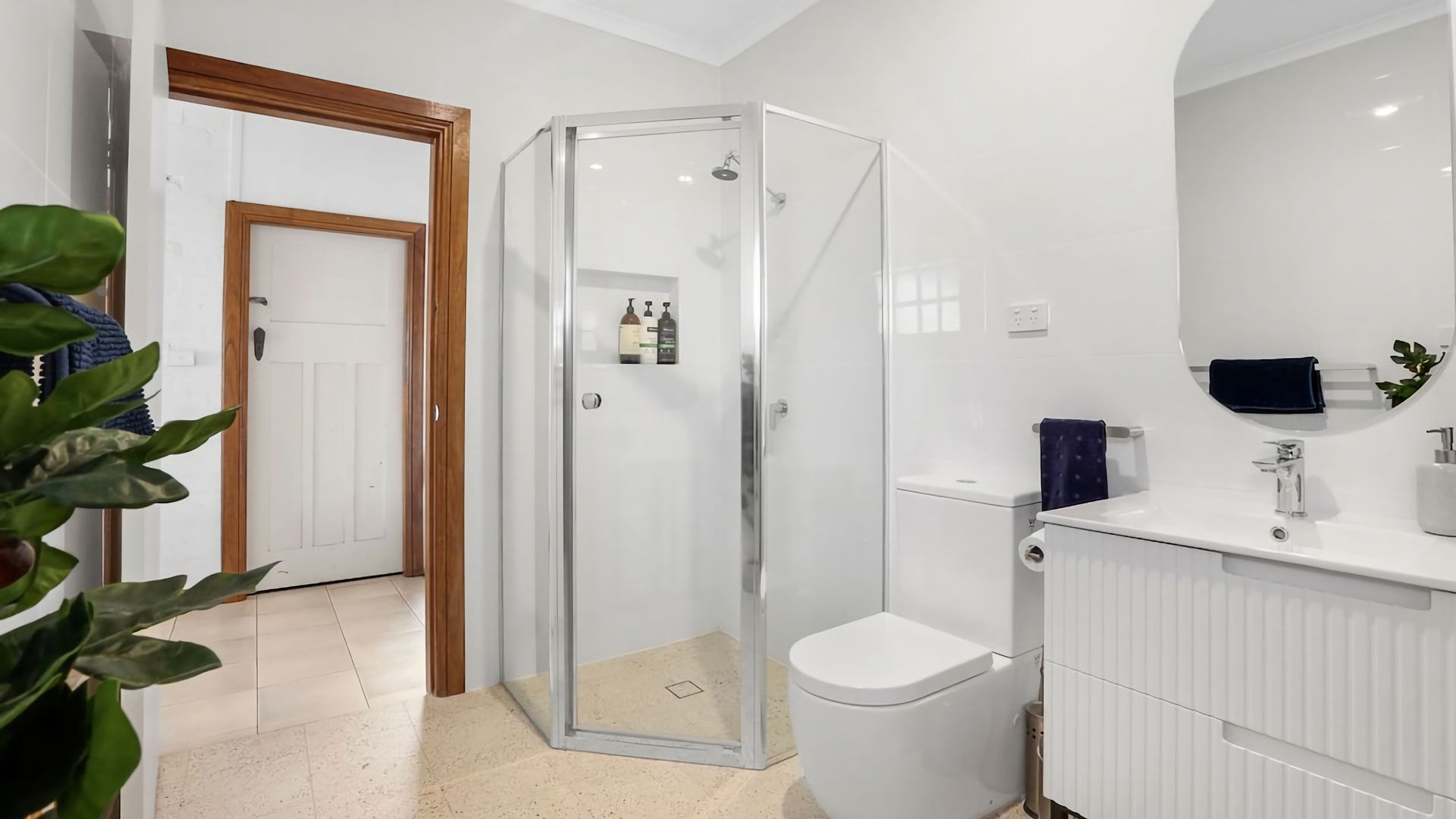 A modern bathroom with a glass shower enclosure, a white toilet, and a sink with a mirror above it.